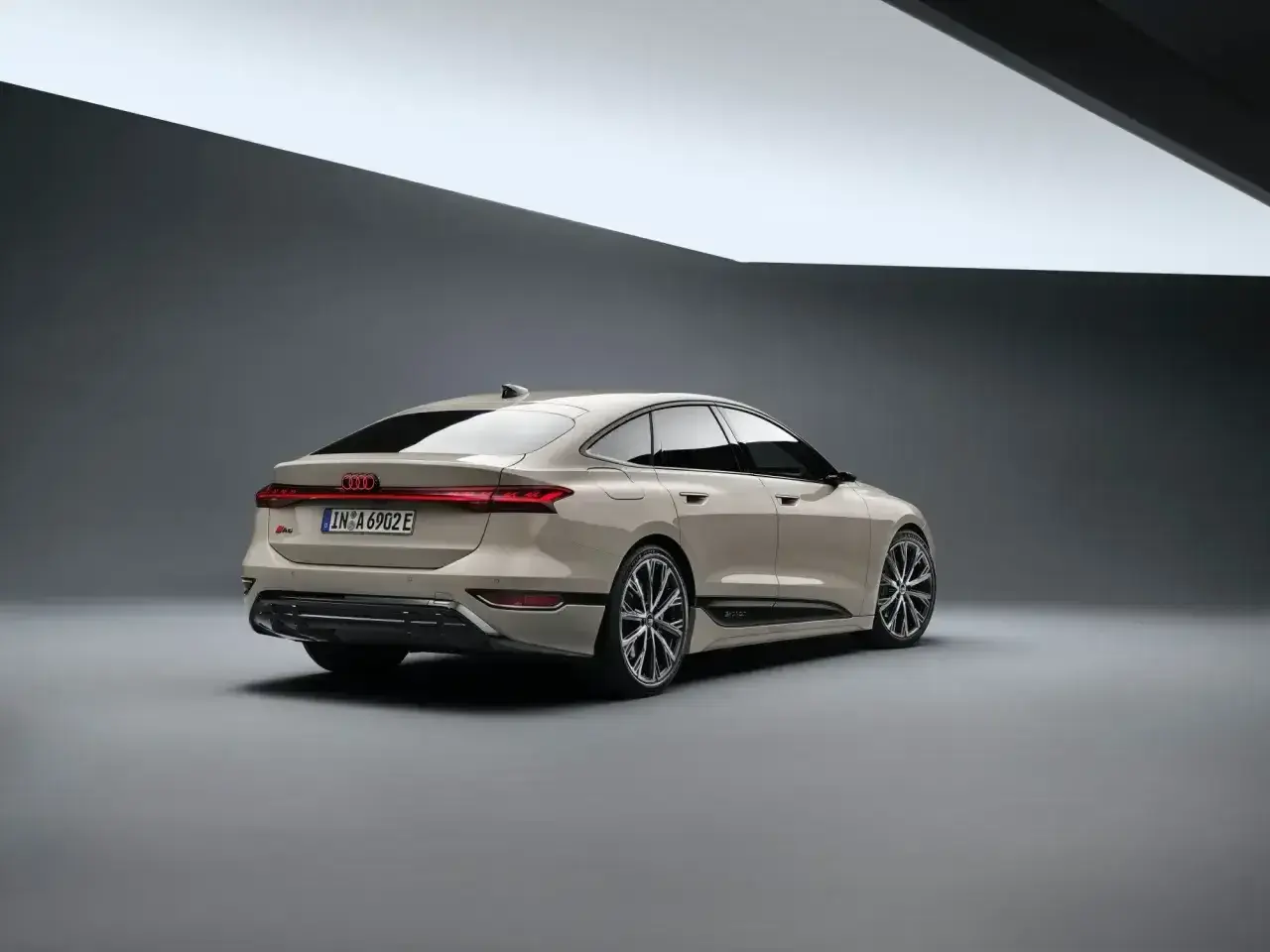 Elegancki tył nowego Audi A6 2025 w kolorze piaskowym, z charakterystycznym pasem świateł LED i sportowymi felgami.