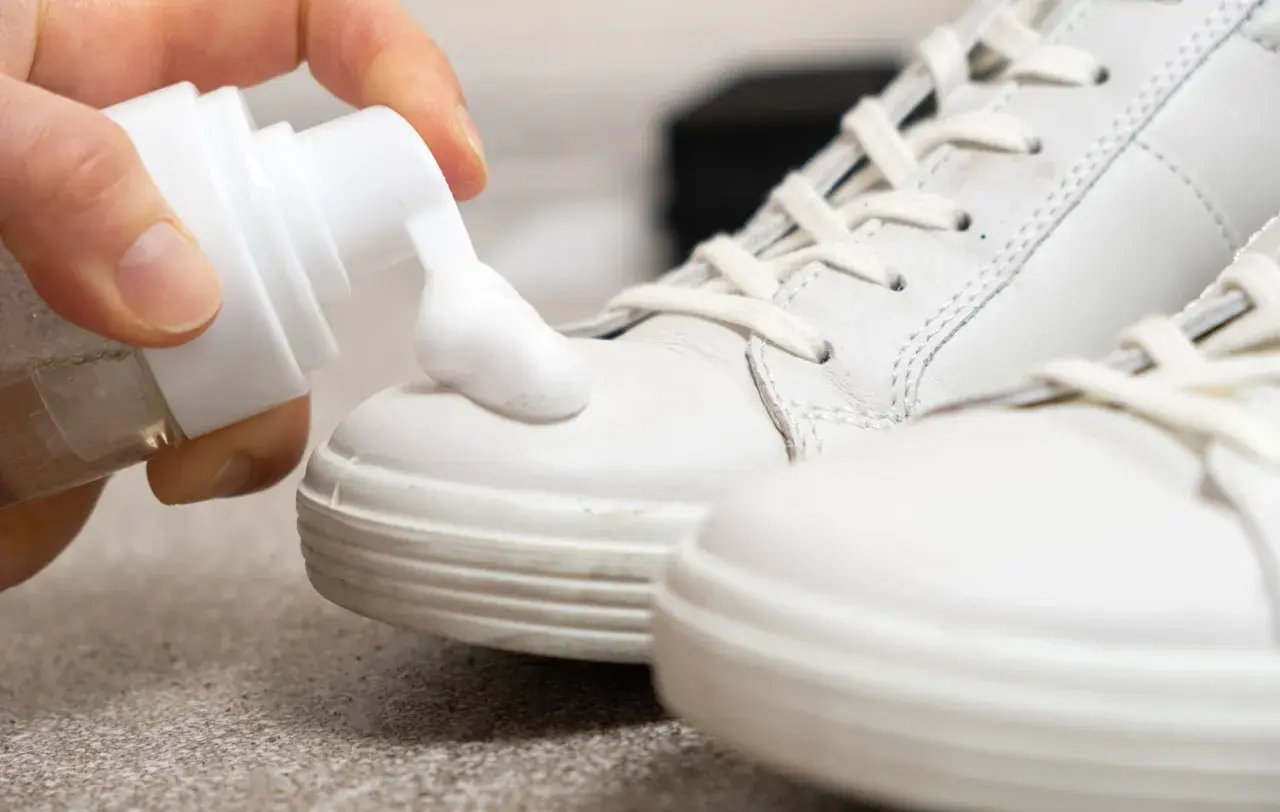 Schaum wird auf weiße Sneaker aufgetragen, um helle Schuhe reinigen.