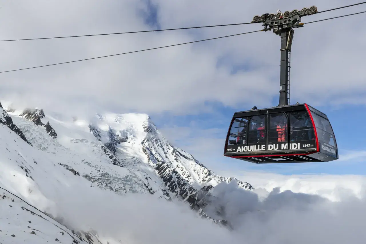 La télécabine de l'Aiguille du Midi survole un paysage alpin spectaculaire, transportant des passagers vers les sommets enneigés.