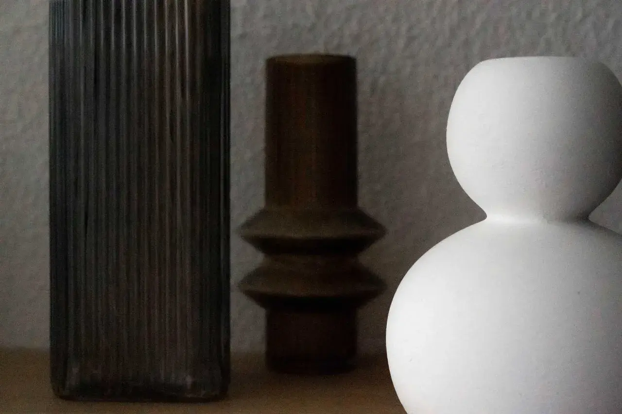 Drei Vasen in verschiedenen Formen und Farben: eine hohe, geriffelte dunkle, eine braune mit zwei Wölbungen und eine weiße, kugelförmige. Perfekt zum Vase dekorieren ohne Blumen.