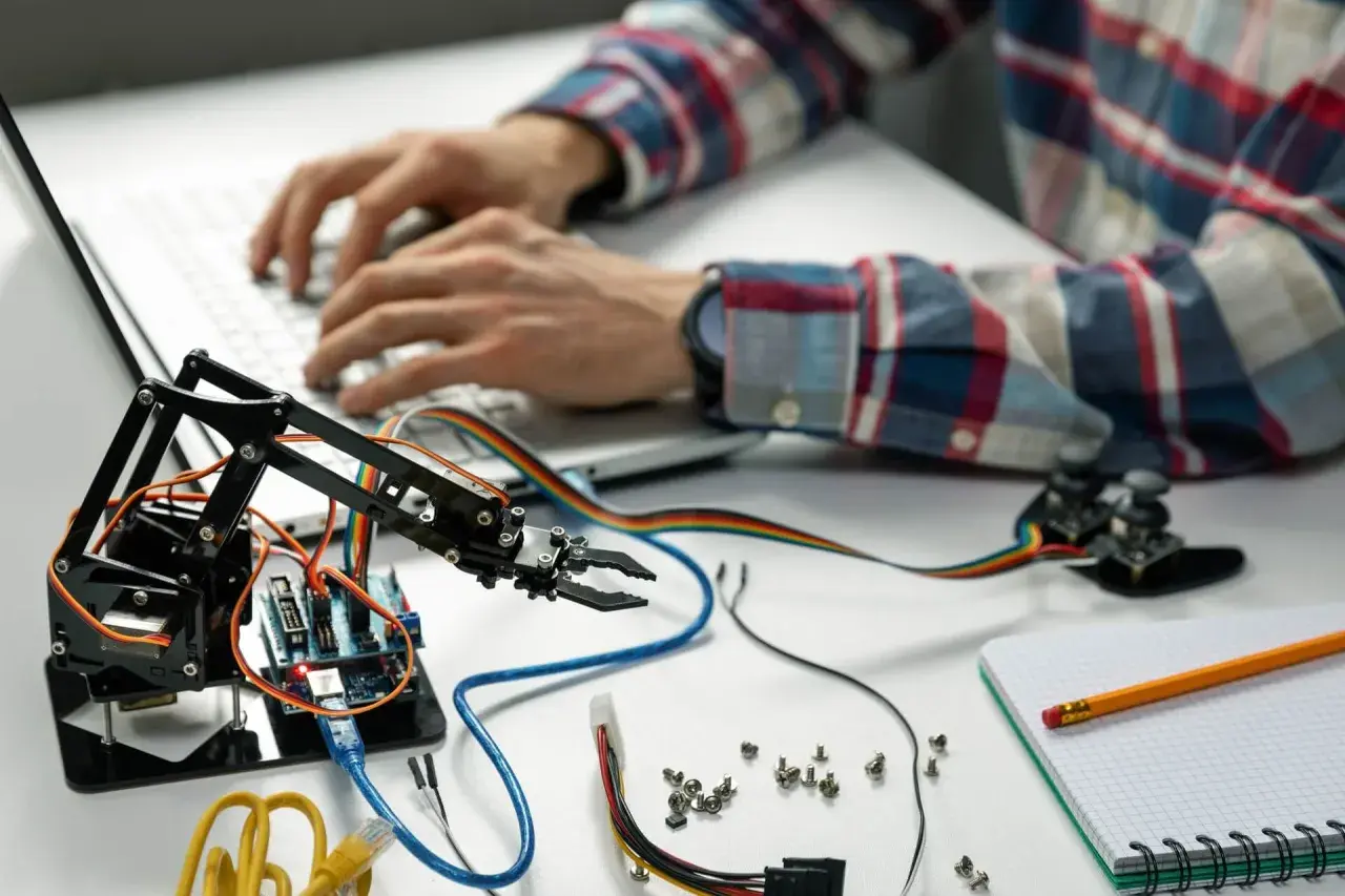 Programista tworzy automatyzację procesów, programując ramię robota na laptopie.