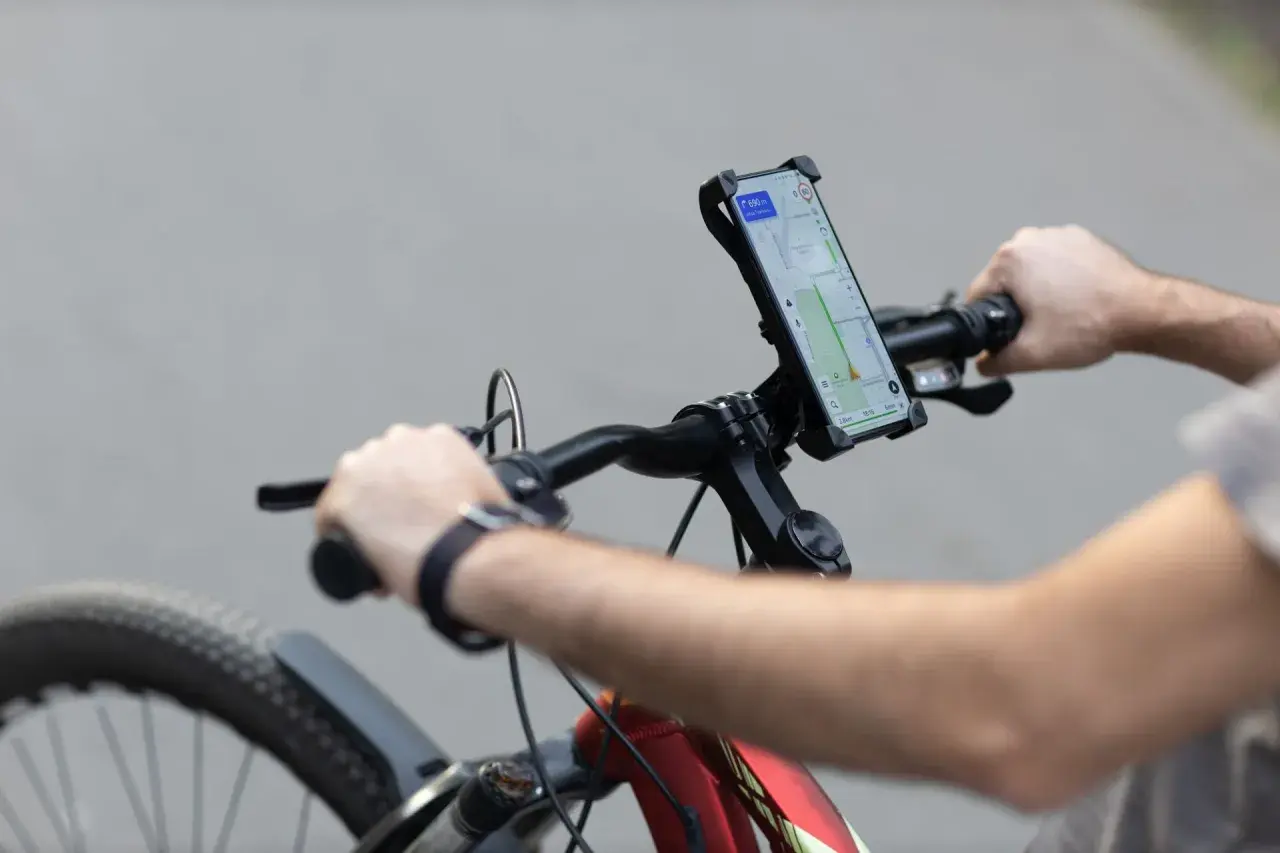 Rowerzysta z telefonem na kierownicy, nawigacja pokazuje trasę. Idealne do śledzenia treningów z Endomondo.