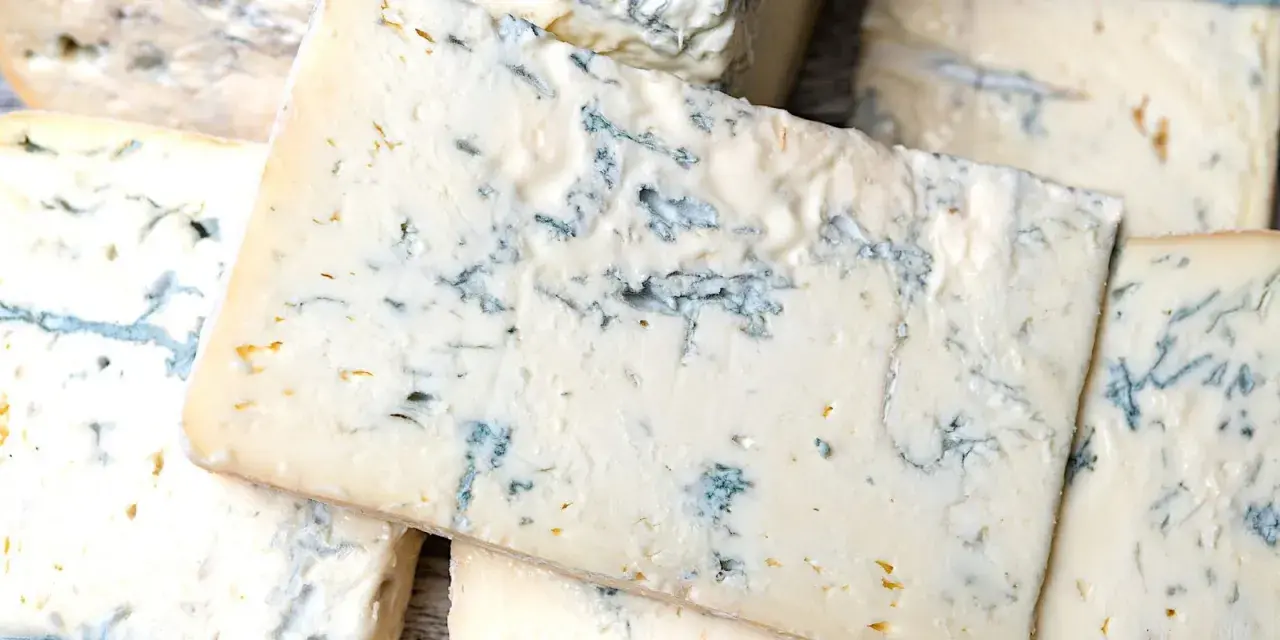 Fette di formaggio verde, con venature blu intenso, che ricordano il sapore deciso del gorgonzola.
