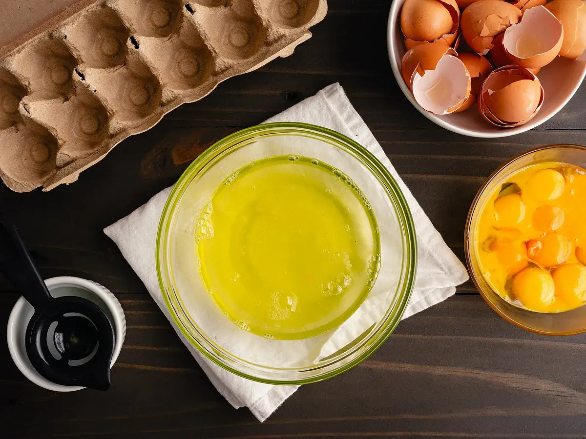 Préparation pour une recette : blancs d'œufs dans un bol, jaunes d'œufs dans un autre, et coquilles dans une coupelle. Le tout prêt à être mis au frigo.