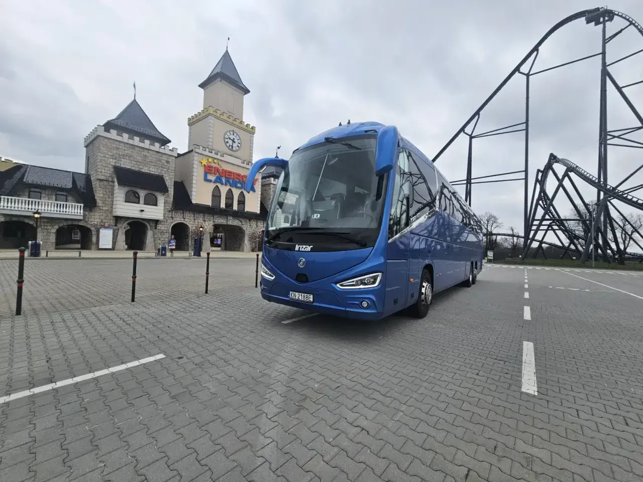 Niebieski autokar przed zamkiem w Energylandii, gotowy na wycieczkę z Wrocławia.