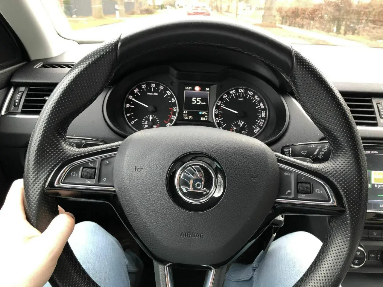 Blick auf das Lenkrad eines Autos mit Tachometeranzeige 55 km/h. Die Spurstange einstellen ist hier nicht direkt sichtbar, aber die Fahrt geht weiter.