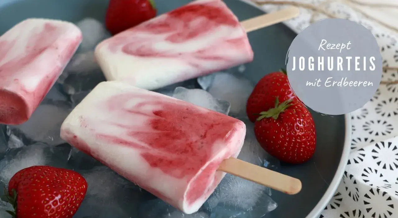 Eis selber machen schnell: Joghurt-Erdbeer-Eis am Stiel auf Eiswürfeln, garniert mit frischen Erdbeeren.