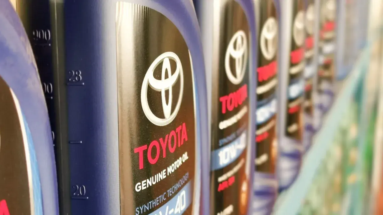 Rząd butelek oryginalnego oleju Toyota. Kto produkuje? Toyota, znana marka samochodów, produkuje również wysokiej jakości oleje silnikowe.