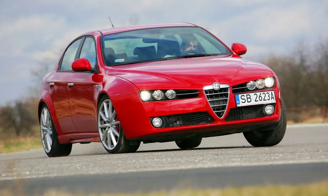 Czerwona Alfa Romeo 159 z włączonymi światłami, widoczne żarówki alfa 159.