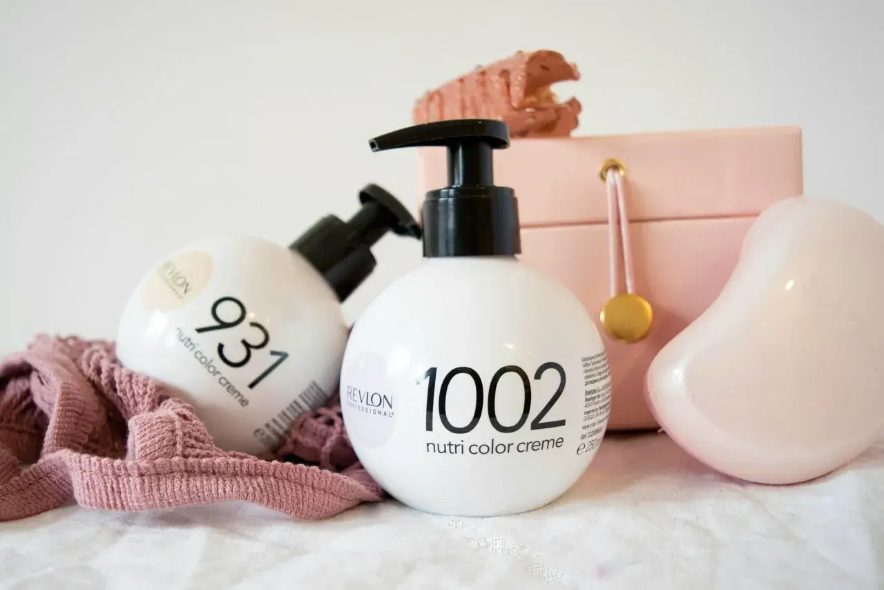 Två flaskor Revlon hårfärg, Nutri Color Creme, står framför en rosa smyckeskrin och en rosa tygbit.