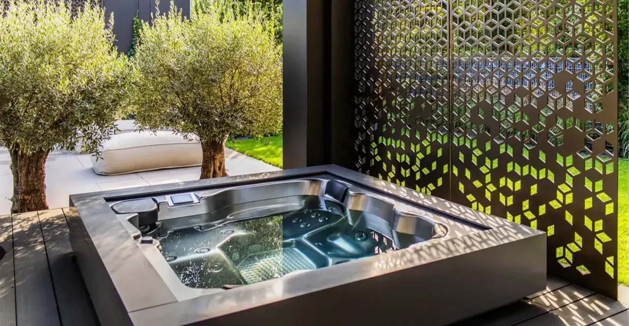 Un jacuzzi moderno en un jardín con olivos y un biombo decorativo. El lugar perfecto para un momento de relax y qué es un chill out.