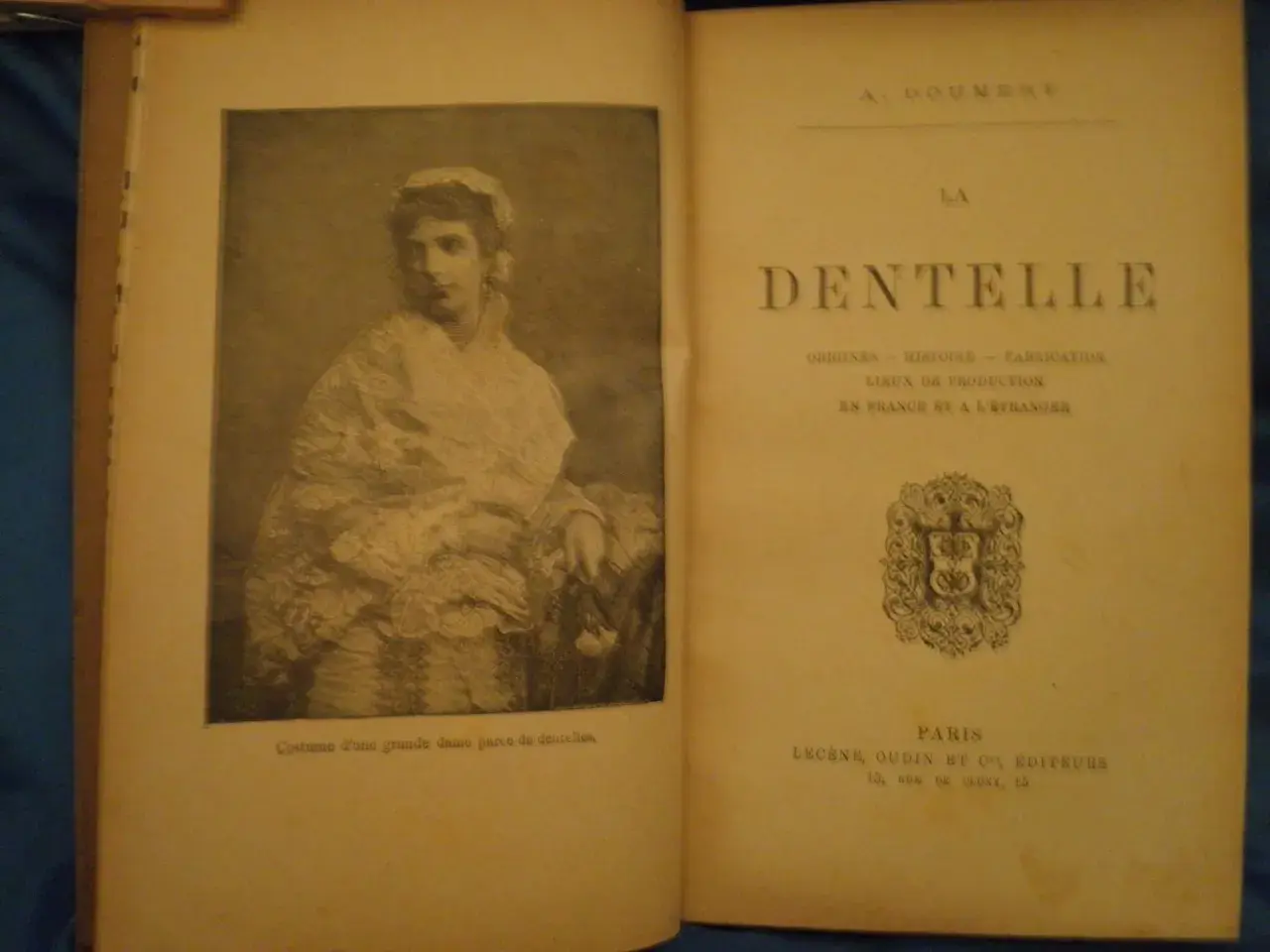 Livre sur la dentelle, avec une gravure de dame en costume orné de dentelles. Le texte évoque l'histoire de la dentelle.