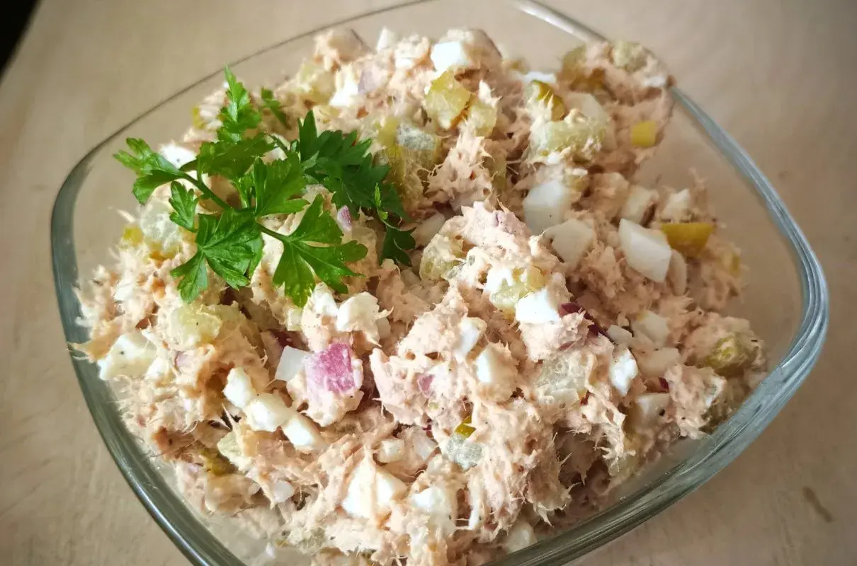 Pyszna pasta z tuńczyka i jajka, z dodatkiem ogórka kiszonego i cebuli, udekorowana natką pietruszki. Idealna na kanapki.