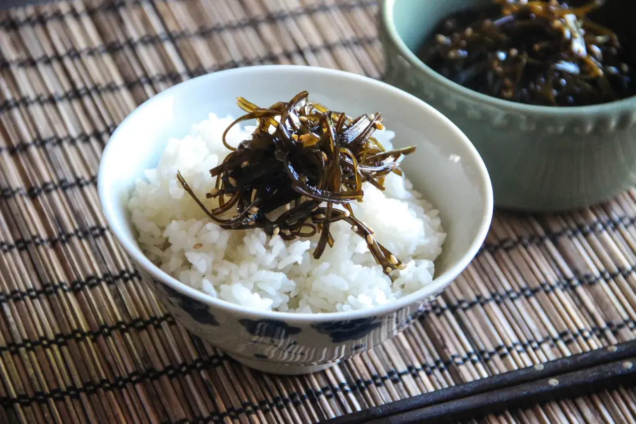 A bowl of white rice topped with dark, glistening tsukudani, a savory seaweed dish. This image hints at a delicious tsukudani recipe.
