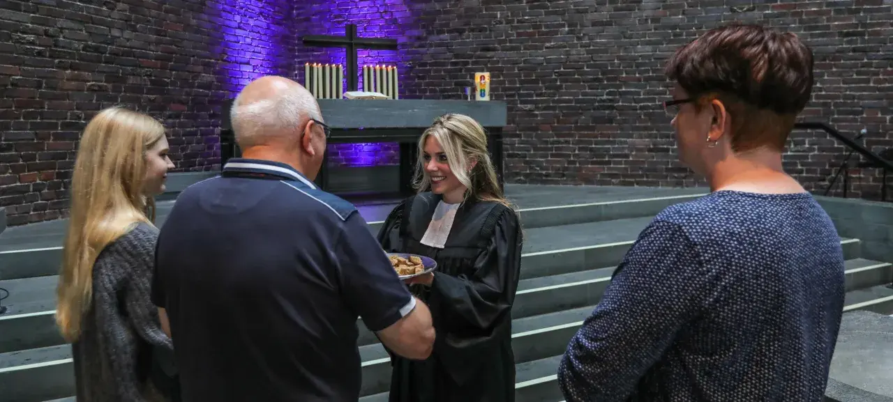 Frauen in der kirche: Eine Geistliche teilt Brot mit Gemeindemitgliedern.
