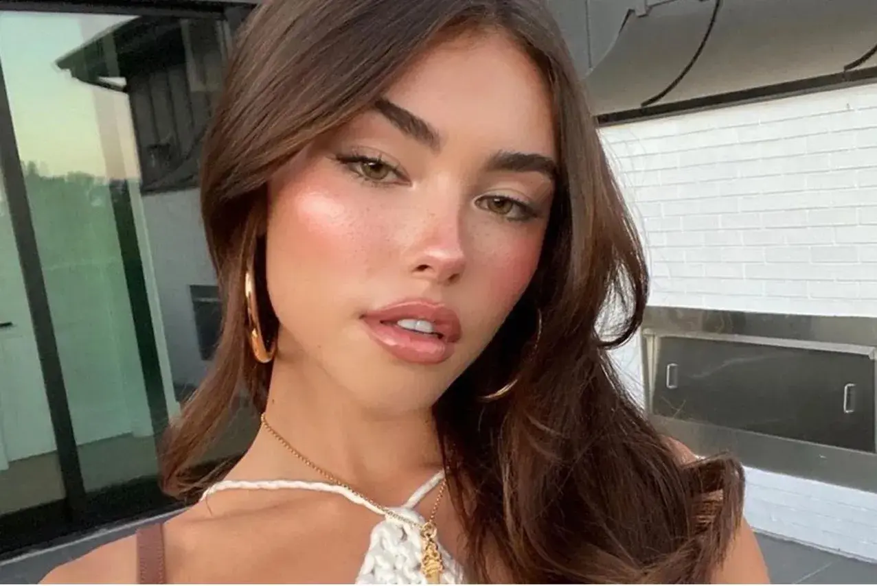 Mujer joven con cabello castaño y maquillaje natural, luciendo un **clean look** con mejillas sonrosadas y labios brillantes.