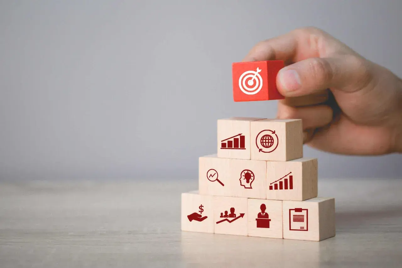 Budowanie strategii marketingowych: klocki symbolizują analizę, pomysły, wzrost, globalny zasięg i cel. Podstawa to marketing fundamentals.