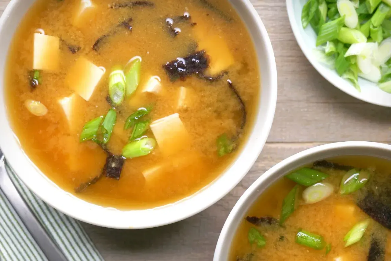 Two bowls of steaming nori soup, filled with tofu cubes and green onions, are ready to be enjoyed.