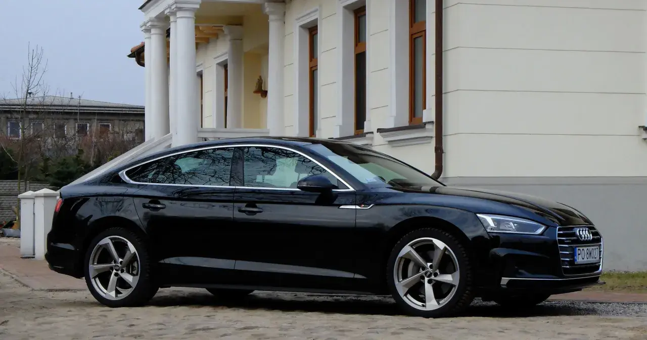 Eleganckie, czarne Audi A5 z 2018 roku zaparkowane przed klasycznym budynkiem z kolumnami.