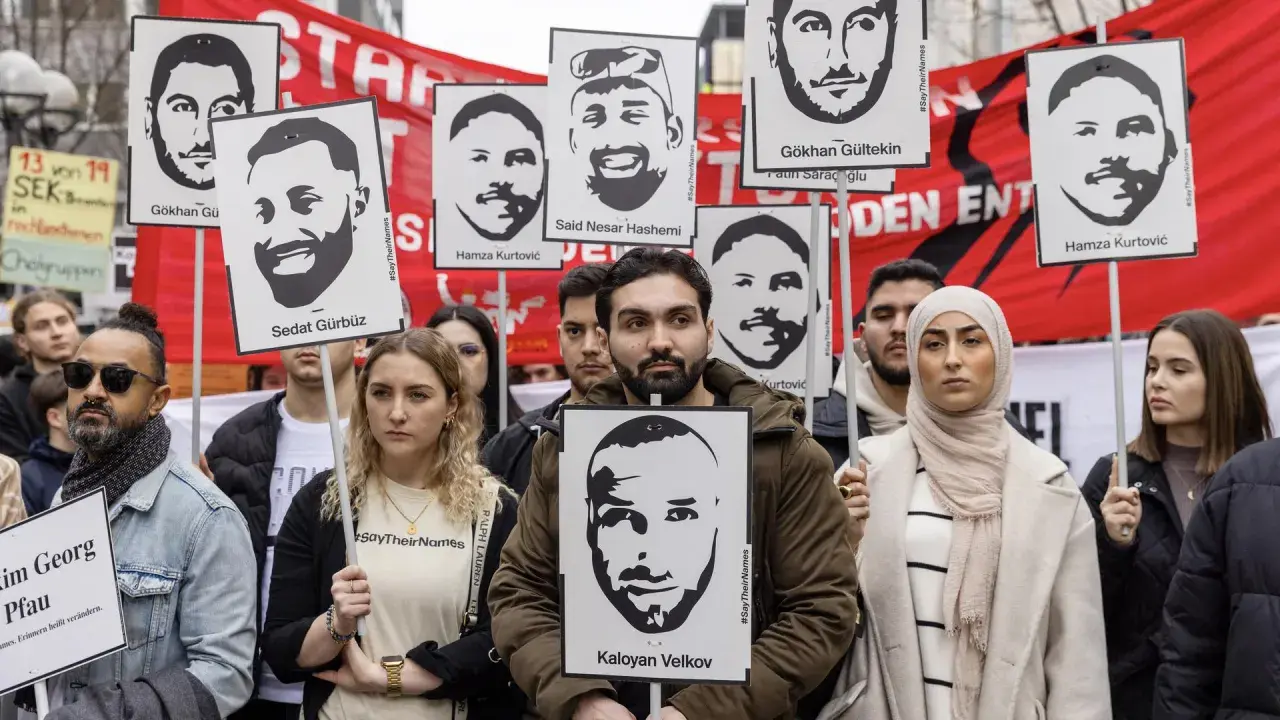 Menschen halten Porträts von Opfern des Hanau-Anschlags hoch. Die Namen der Ermordeten wie Gökhan Gürbüz und Kaloyan Velkov werden gezeigt.