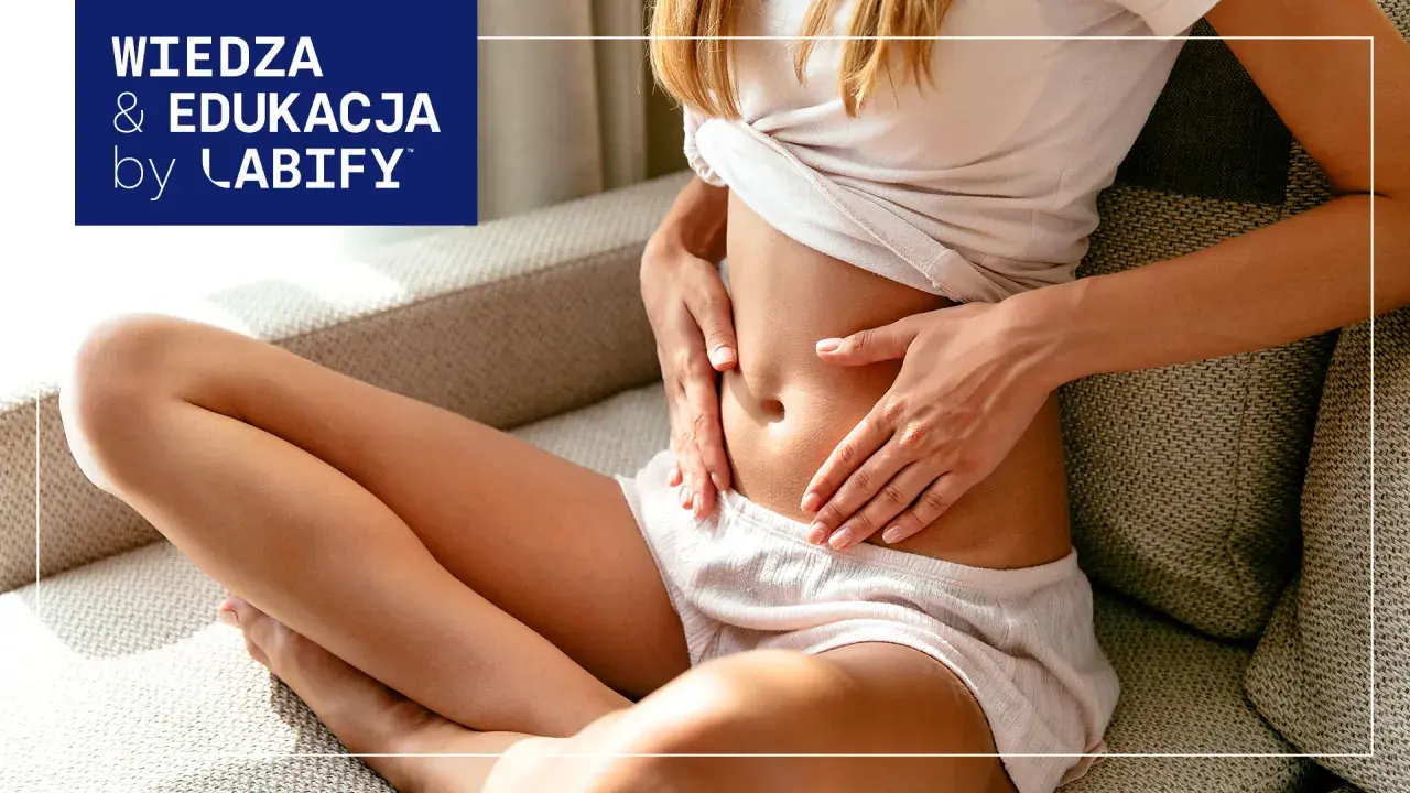 Kobieta trzyma się za brzuch, szukając ulgi co na gazy. Wiedza i edukacja by Labify.