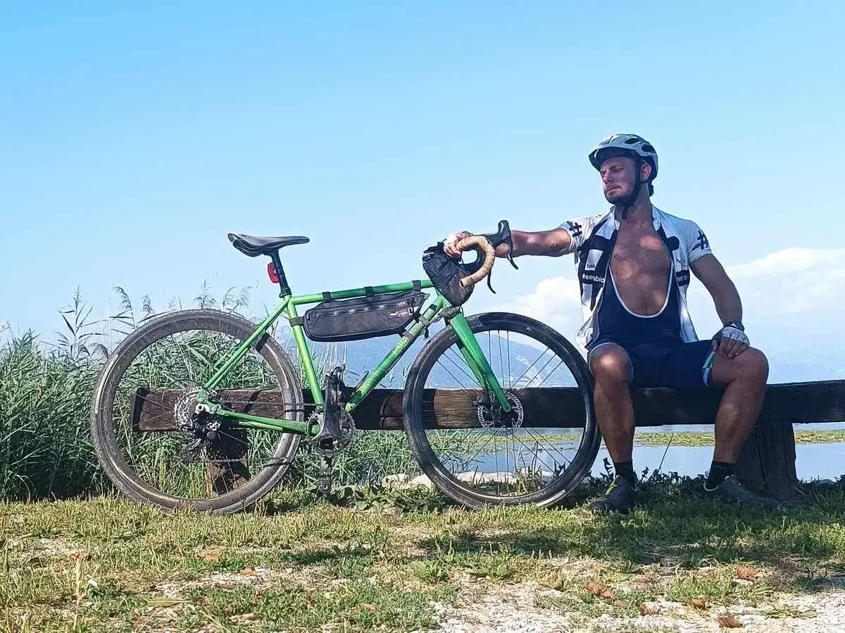 Ciclista riposa accanto alla sua bici verde, un promemoria che andare in bici fa dimagrire e dona benessere.