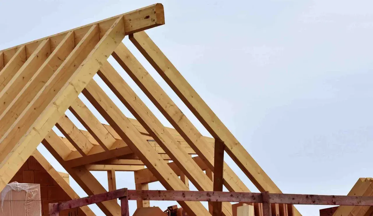 Holzkonstruktion für den dachstuhl aufbau. Balken bilden ein stabiles Gerüst gegen den hellblauen Himmel.