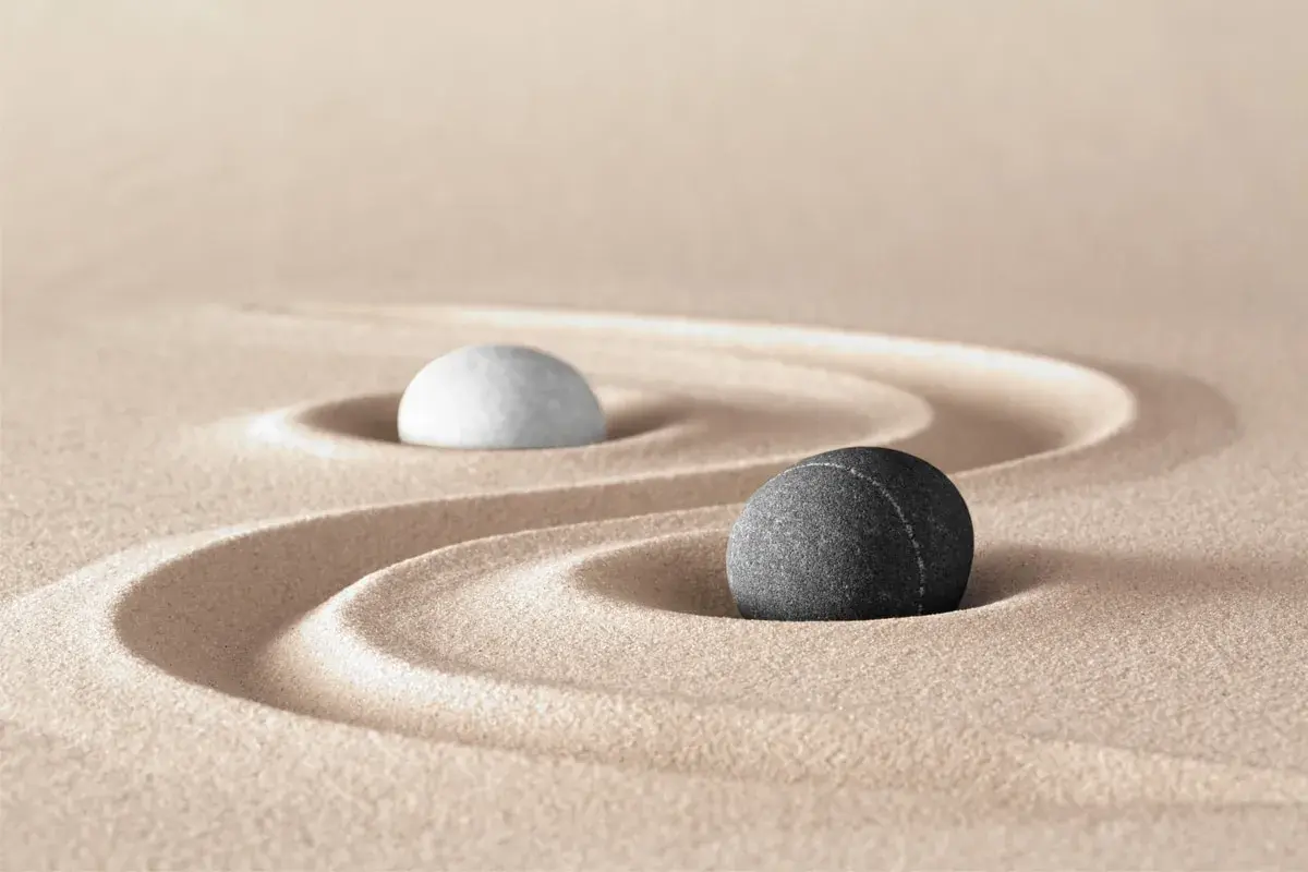 Due pietre, una bianca e una grigia, su sabbia rastrellata, evocano le yin e yang caratteristiche di equilibrio e dualità.