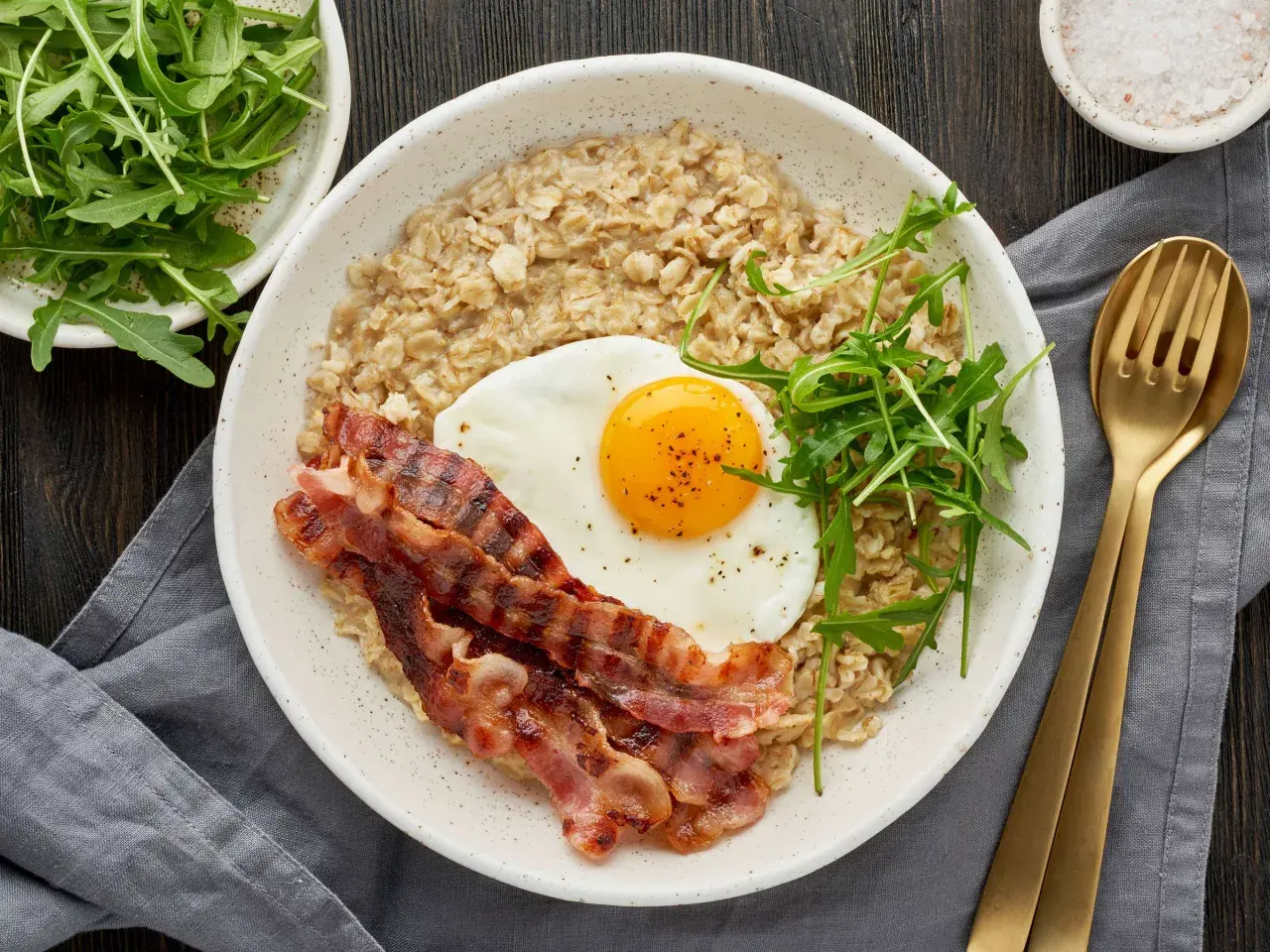 Herzhaftes Frühstück: Haferflocken mit Spiegelei, Speck und Rucola. Wer sagt, dass man Haferflocken abends essen muss? Dieses Gericht ist perfekt für einen energiegeladenen Start in den Tag.
