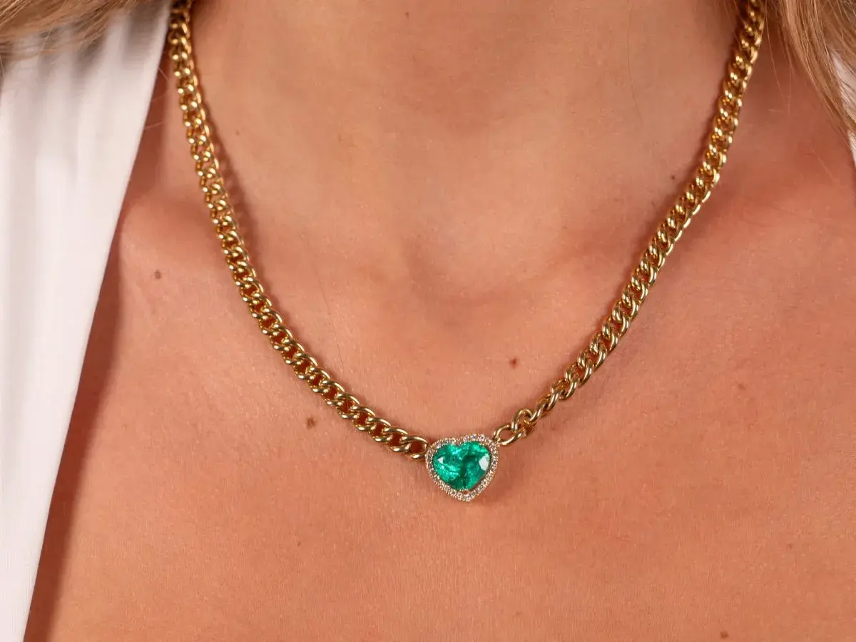 Collar de oro con colgante de corazón de esmeralda y diamantes. Un ejemplo de nombres de joyas que evocan elegancia y amor.
