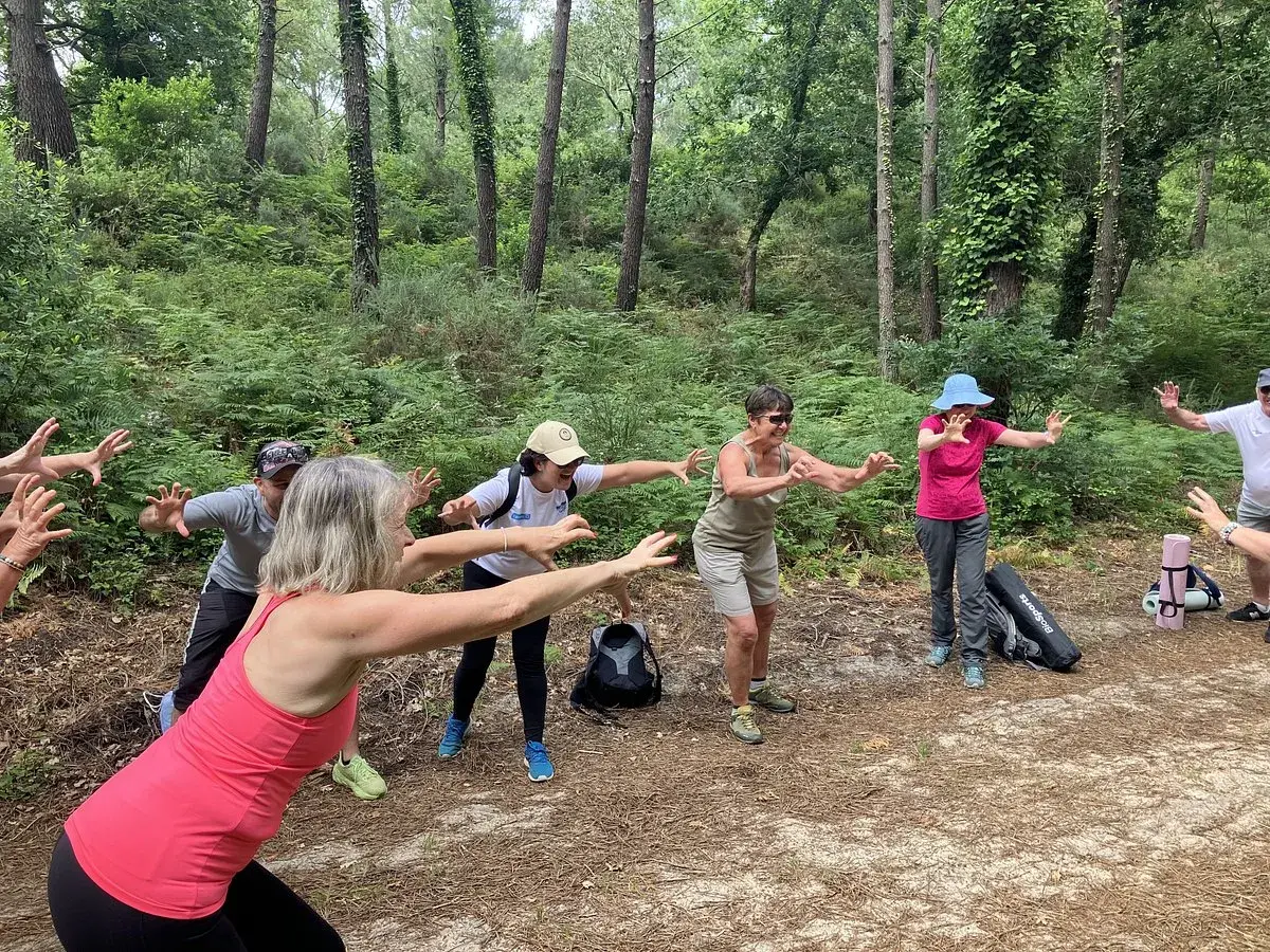 Groupe pratiquant le shinrin yoku en forêt, bras tendus, profitant de la nature.