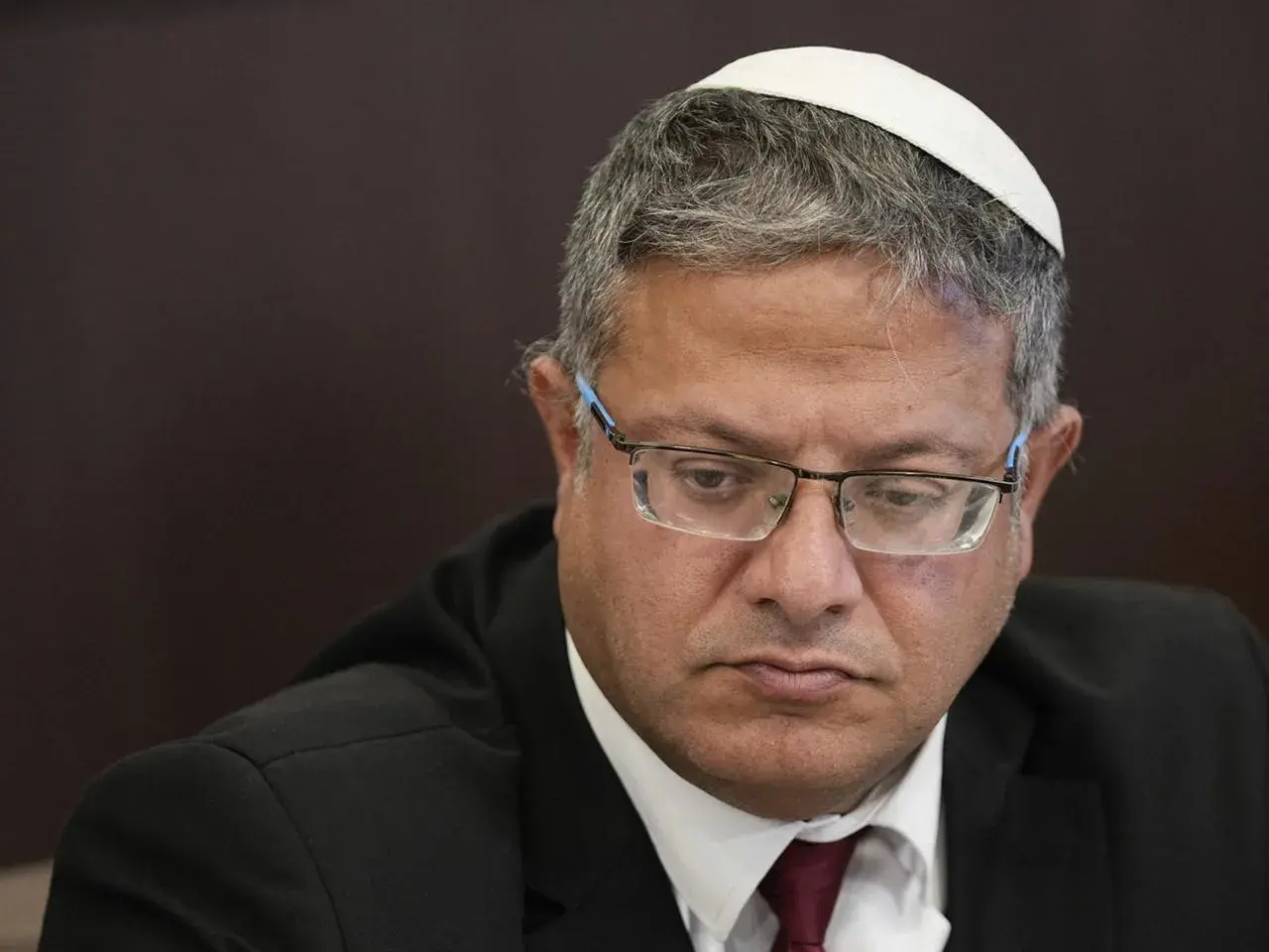 Ein israelischer Politiker mit Kippa und Brille, der nachdenklich nach unten blickt.