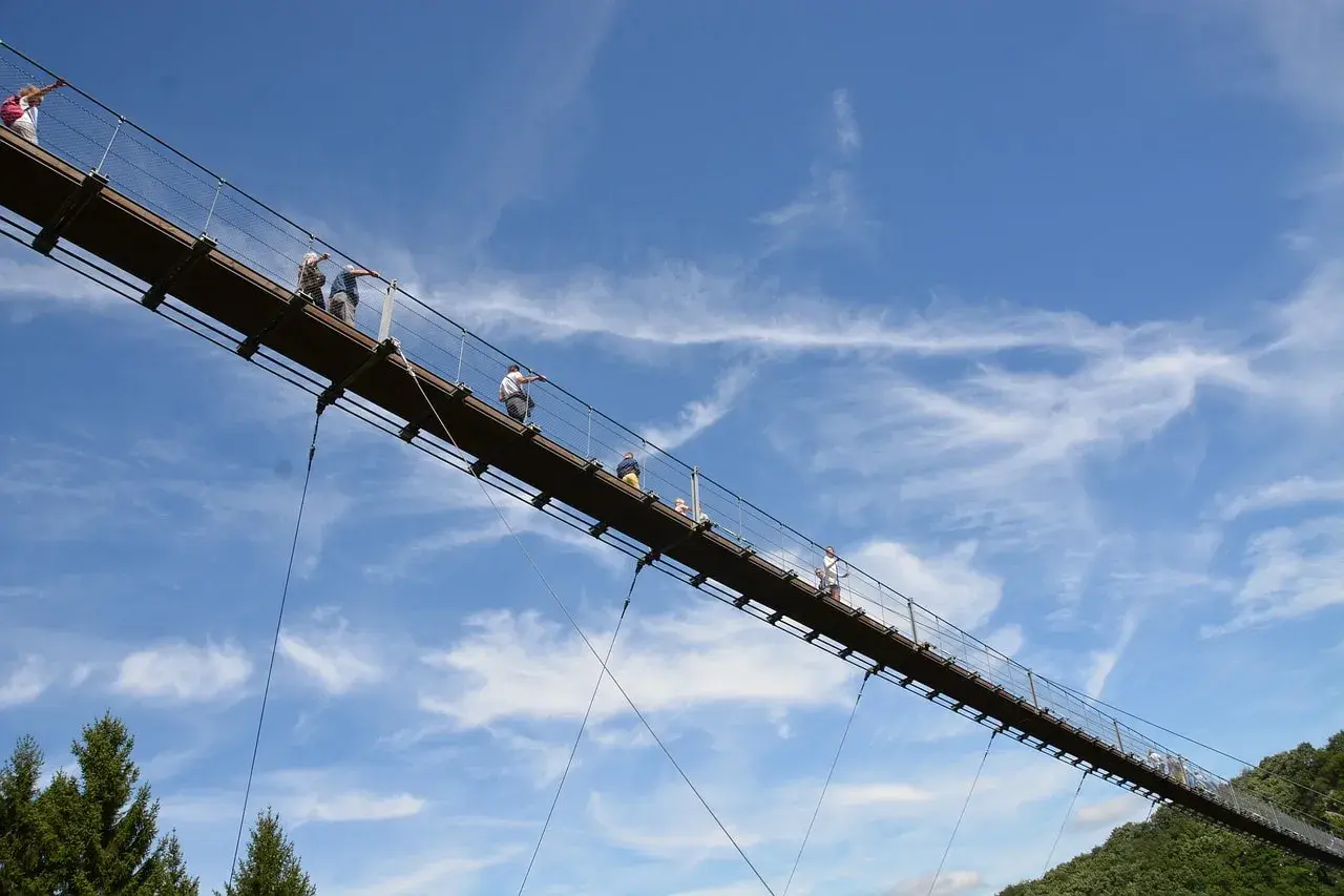 Menschen spazieren auf einer Hängebrücke im Himmel. Ein tolles geheimes Ausflugsziel in Rheinland-Pfalz für Abenteuerlustige.