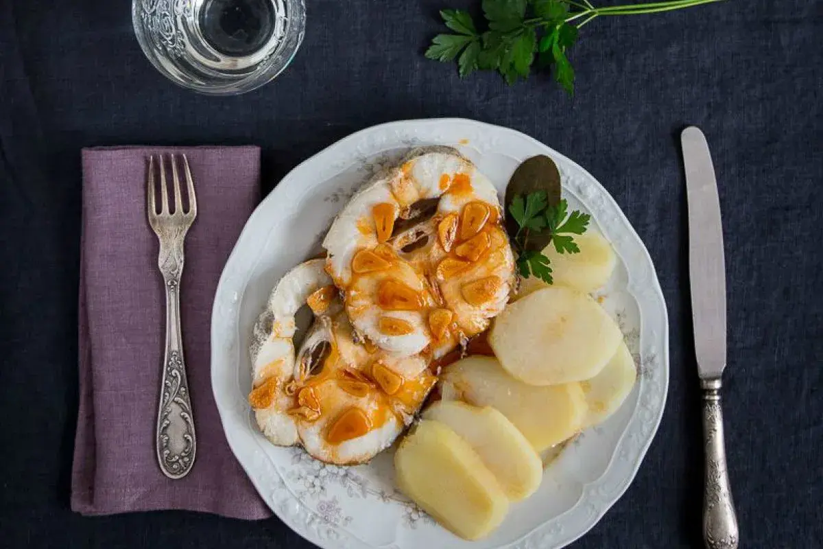 Merluza a la gallega con patatas cocidas, ajo dorado y perejil. Un plato tradicional listo para disfrutar.