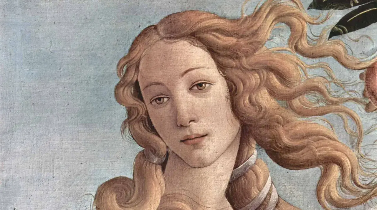 The face of Venus, a timeless muse in art, with flowing golden hair against a pale blue sky.
