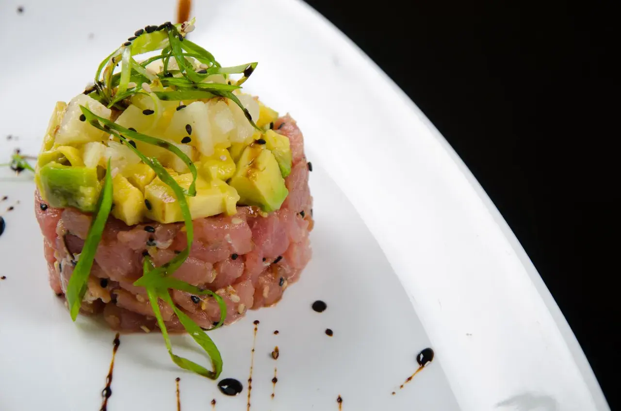 Deliziosa tartare di tonno con avocado e ananas, guarnita con erba cipollina e semi di sesamo nero.