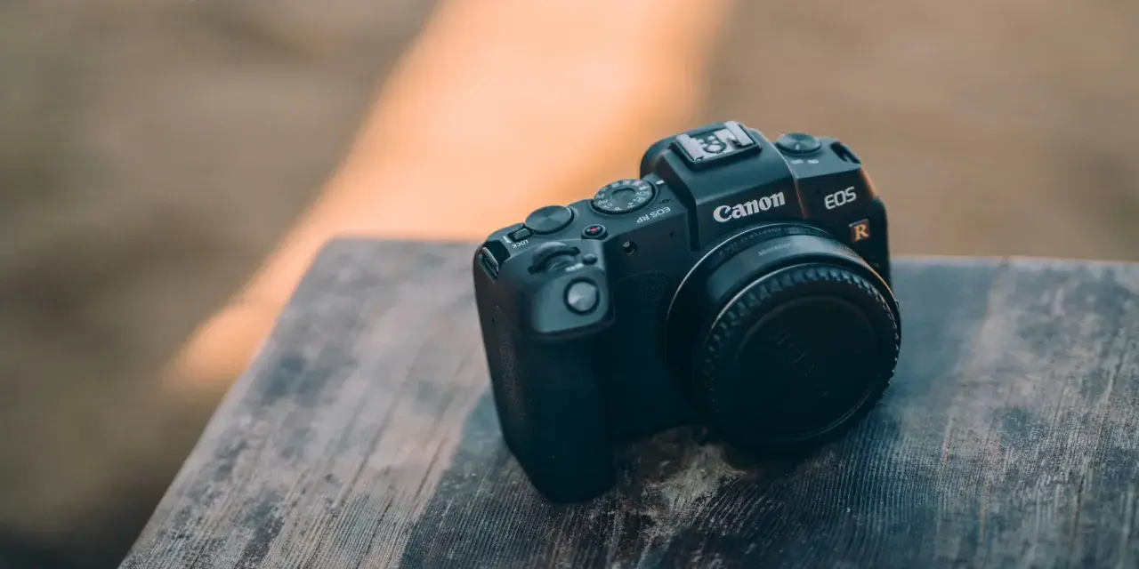 Czarny aparat Canon EOS RP leży na drewnianym blacie. Idealny do canon rp testów.