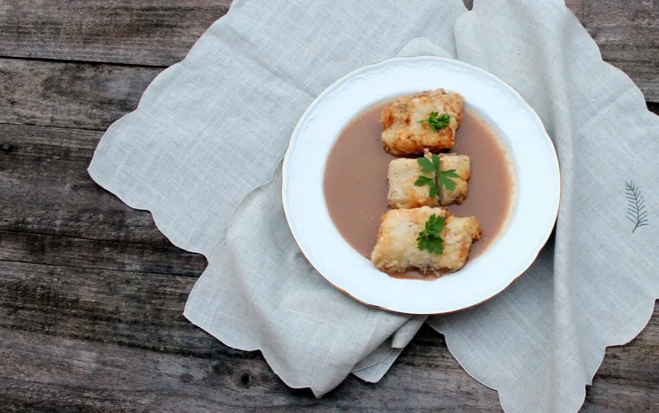 Tres trozos de bacalao rebozado en una salsa cremosa, decorados con perejil. Una de las muchas deliciosas recetas de bacalao.