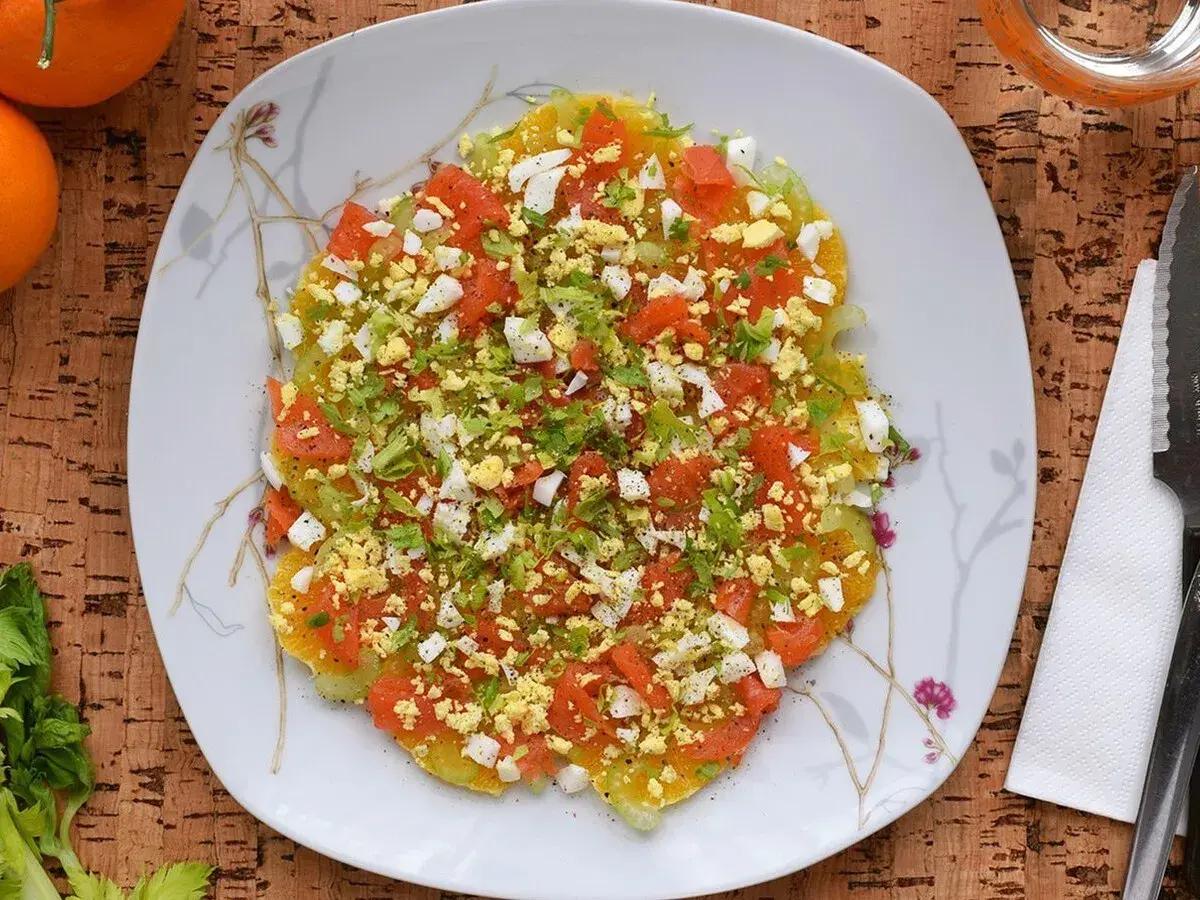 Deliciosa ensalada de invierno con rodajas de naranja, tomate picado, huevo duro y perejil fresco.
