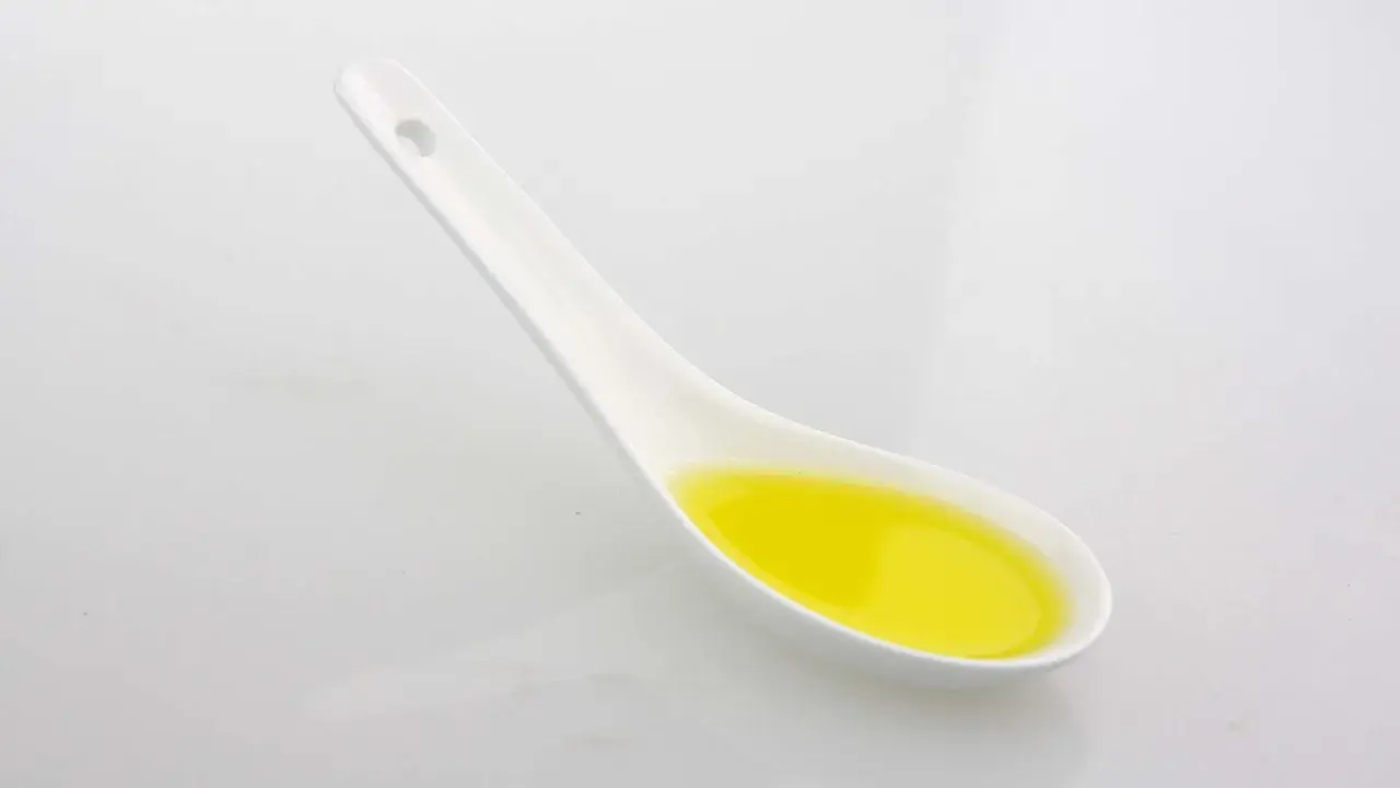 Ein Löffel mit goldenem Olivenöl. Achten Sie auf die Olivenöl Kalorien, wenn Sie es genießen.
