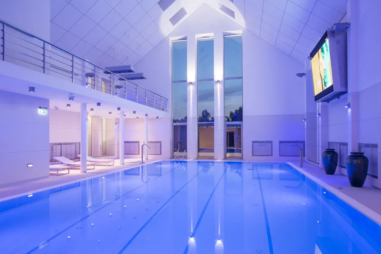 Basen w narie resort & spa, oświetlony niebieskim światłem, z leżakami i dużymi oknami.