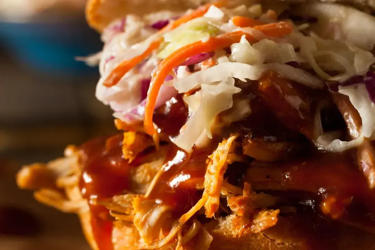 Gros plan sur un sandwich gourmand : effiloché de porc savoureux, sauce barbecue onctueuse et salade de chou croquante. Un délice !