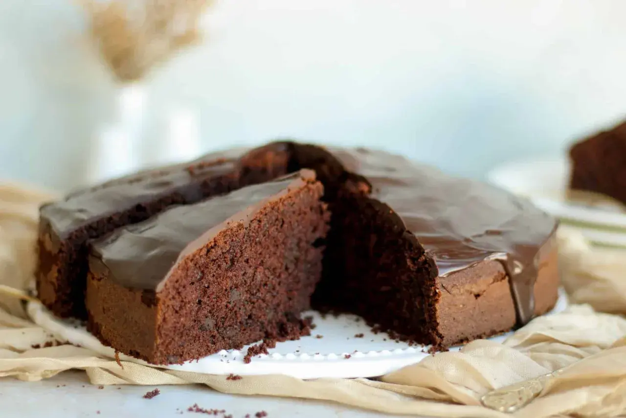 Saftiger Schokokuchen mit glänzender Glasur, perfekt für ein schnelles schokokuchen rezept. Ein Stück ist bereits angeschnitten.