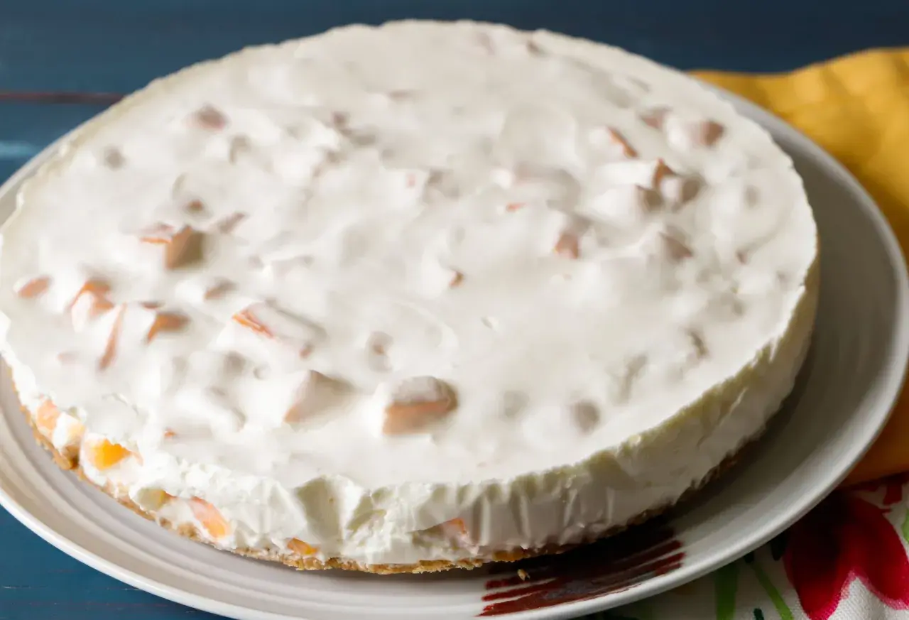 Torta fredda con una soffice crema al melone e pezzetti di frutta arancione.