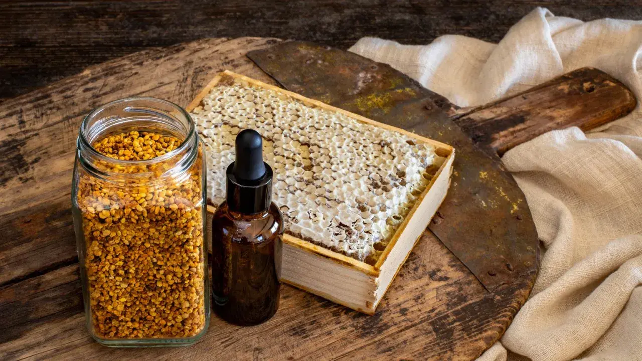 Słoik z pyłkiem pszczelim, buteleczka z kroplomierzem i plaster miodu. Naturalne składniki, które mogą posłużyć jako propolis lek.