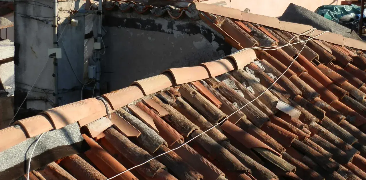 Dettaglio di un vecchio tetto con tegole in terracotta danneggiate, un esempio di come sistemare un vecchio tetto per ripristinarne l'integrità.