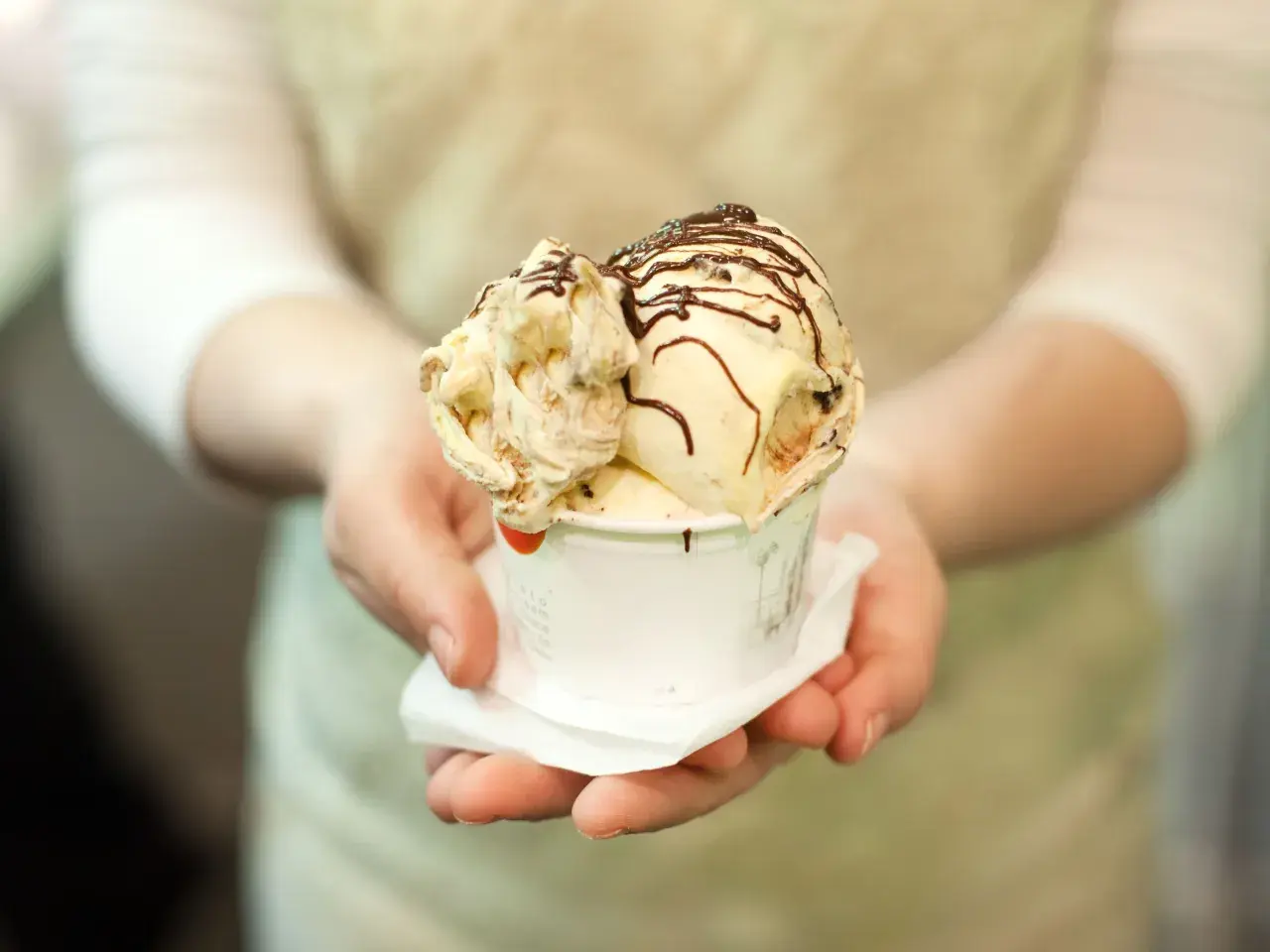 Un cono di gelato artigianale, con variegature e scaglie di cioccolato, pronto per essere gustato, un assaggio della storia del gelato.
