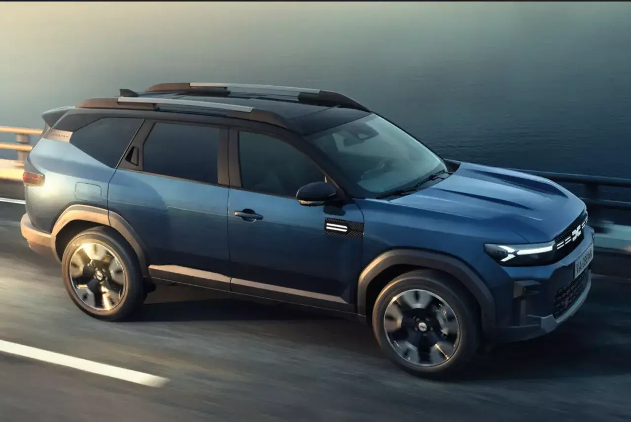 Niebieski Dacia Bigster 2025 na drodze, z nowoczesnym designem i relingami dachowymi.