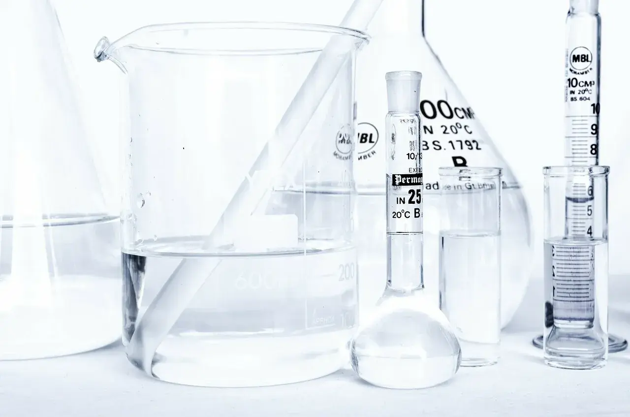 Laboratorium z naczyniami szklanymi, w tym zlewką z płynem i pipetą z oznaczeniem "caprylyl glycol".