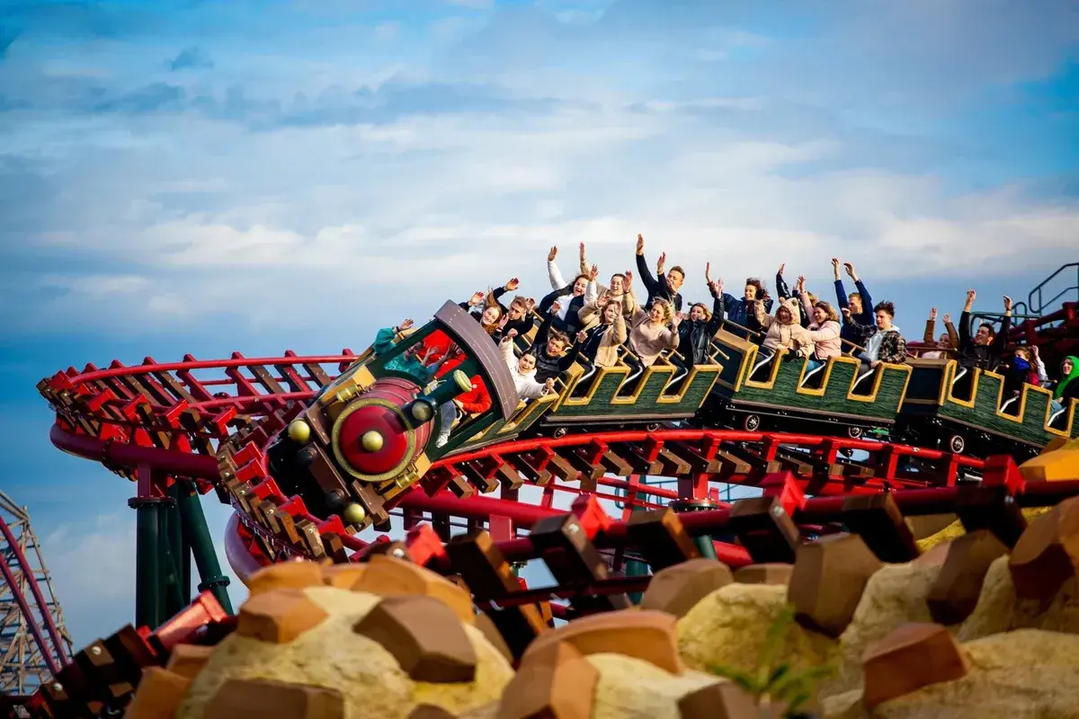 Energylandia pociąg z pasażerami wznosi się na torach kolejki górskiej, wszyscy krzyczą z radości.